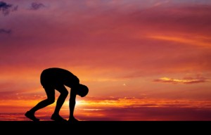 Silhouette of athlete in position to run on sunset background