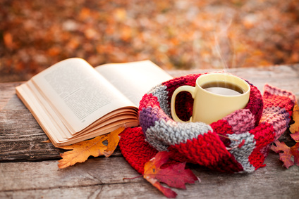 Open book and yellow tea mug with warm scarf