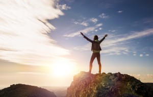 the girl stands on top of the mountain and enjoys the view of the valley. at the dawn, hands up