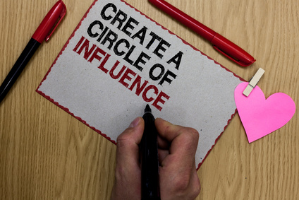 Text sign showing Create A Circle Of Influence. Conceptual photo Be an influencer leader motivate other people Written sticky note clip pinch heart hand hold marker red pen on wooden desk.